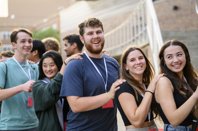 Smiling students at SOAR, lined up with their hands on the shoulders of the person in front of them